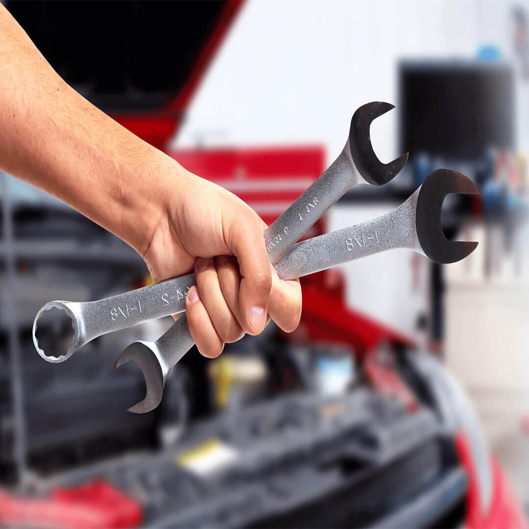 A hand closed up of a man holding a wrench with an under-hood