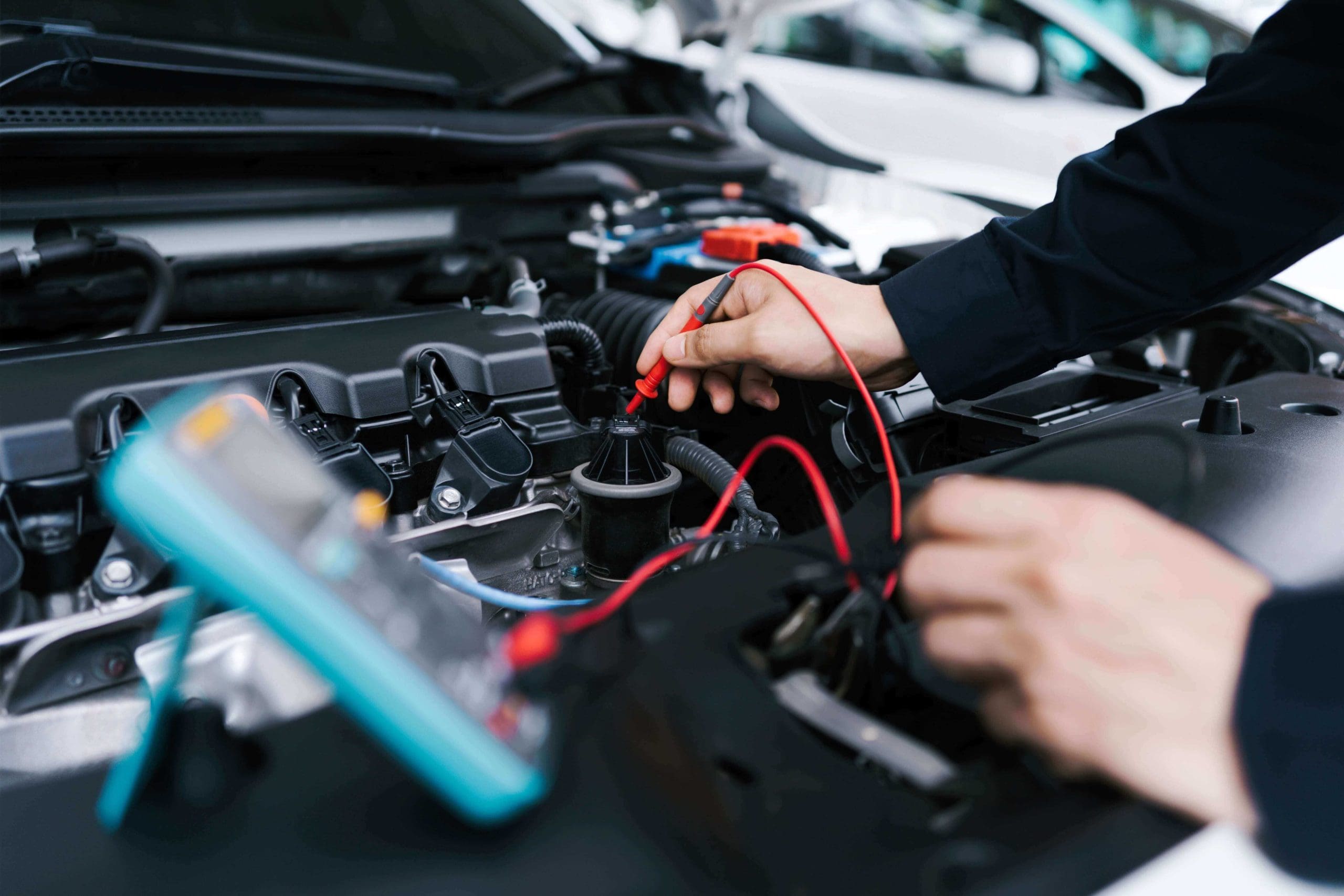 Diagnosing a Cadillac car with a blue color multimeter underhood