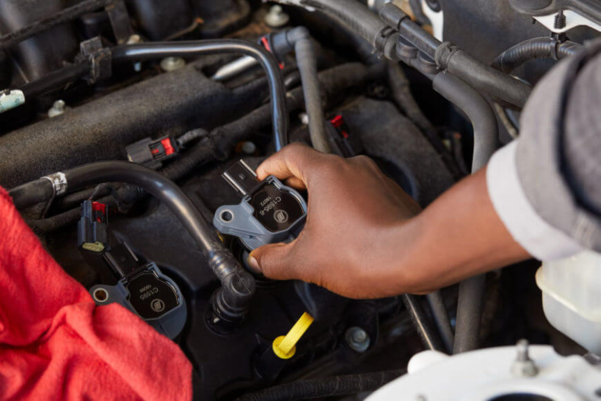 Man holding a Cadillac ignition coil underhood