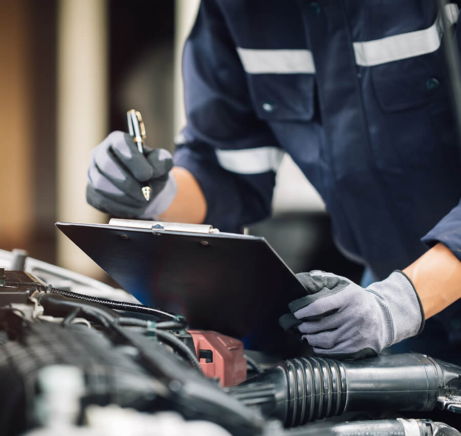 Service mechanic under the hood doing quality assurance checklist