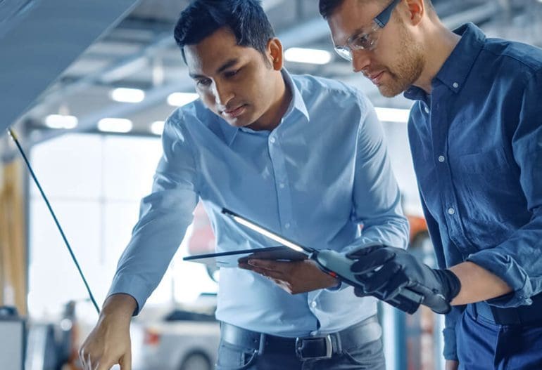 Two professional-looking service mechanics under hood testing and checking