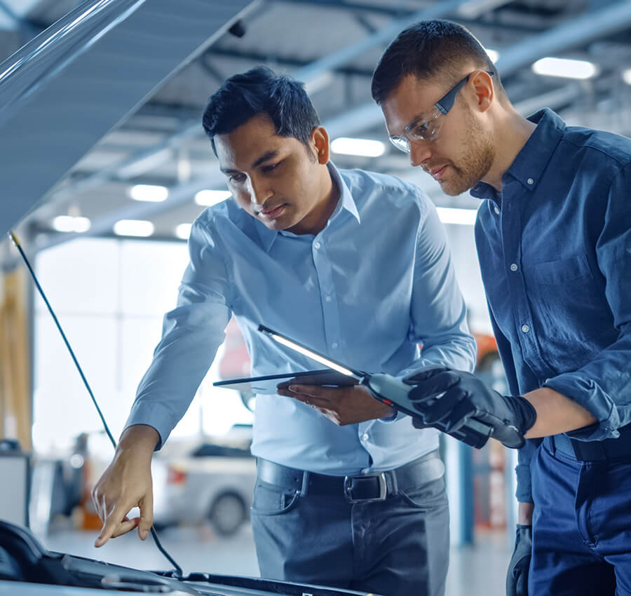 Two professional-looking service mechanics under hood testing and checking