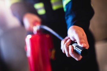 Man holding a fire extinguisher, demonstrating essential fire safety tips for preventing and managing fires at home.