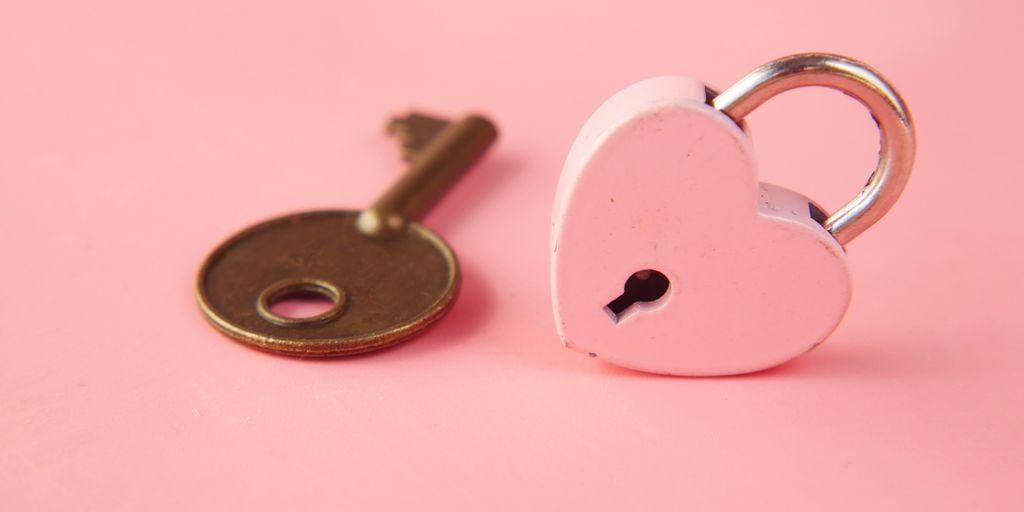 a heart shaped lock and a key on a pink background